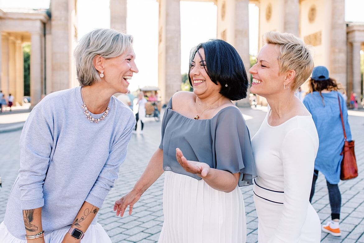 Drei Frauen lachen vor dem Brandenburger Tor Berlin