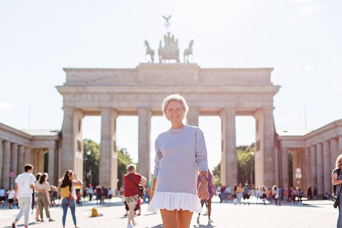 Eine Frau läuft vor dem Brandenburger Tor angestrahlt von der Sonne