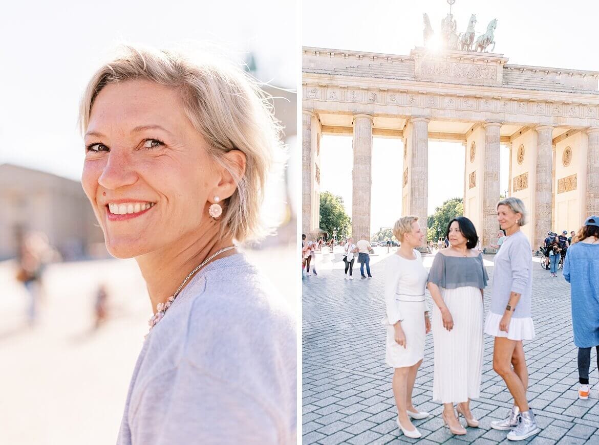 Eine Frau mit blonden Haaren schaut lachend in die Kamera. Drei Frauen verschwommen vor dem Brandenburger Tor Berlin