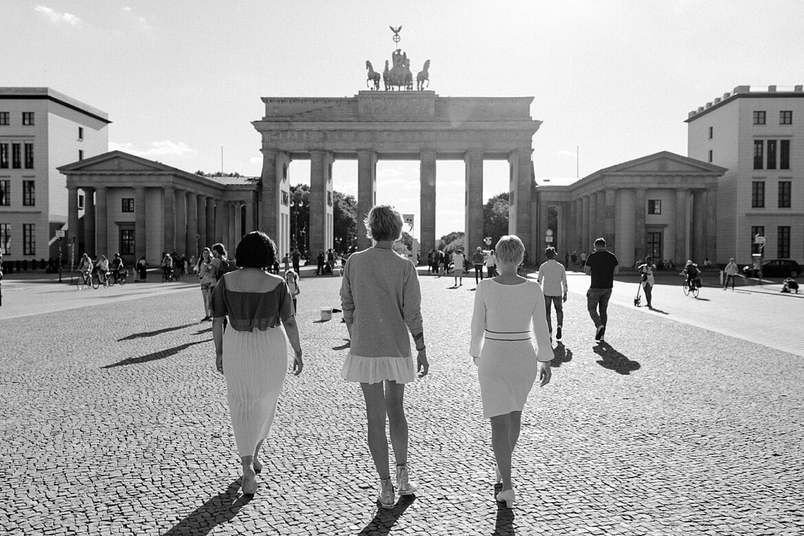 Schwarz Weiß Aufnahme von drei Frauen, die zum Brandenburger Tor Berlin laufen