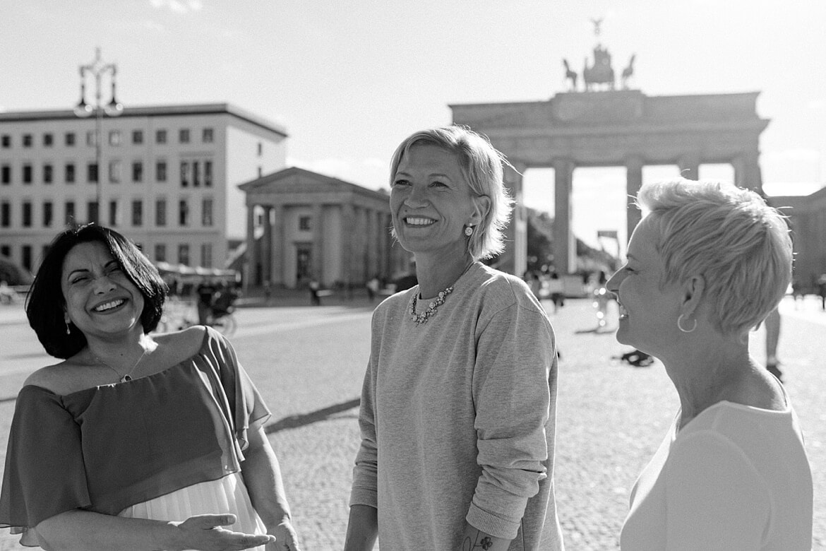 Schwarz weiß Foto von drei lachenden Frauen vor dem Brandenburger Tor Berlin