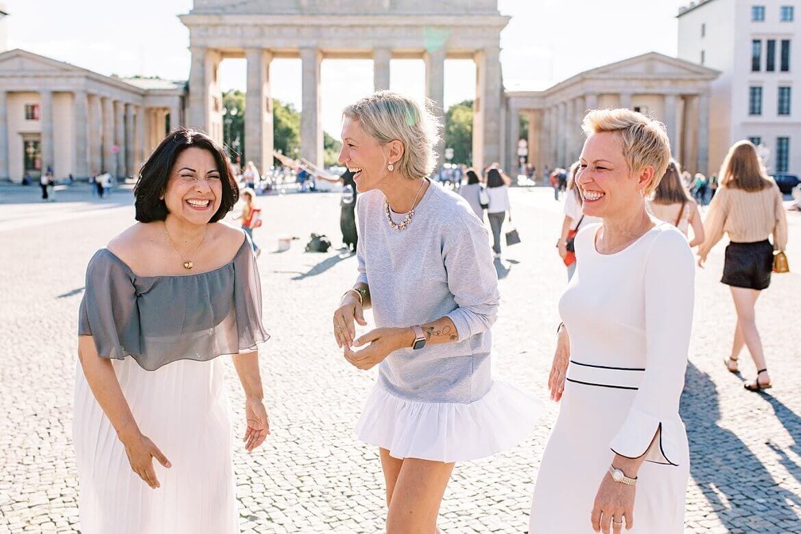 Drei Frauen lachen gemeinsam vor dem Brandenburger Tor Berlin