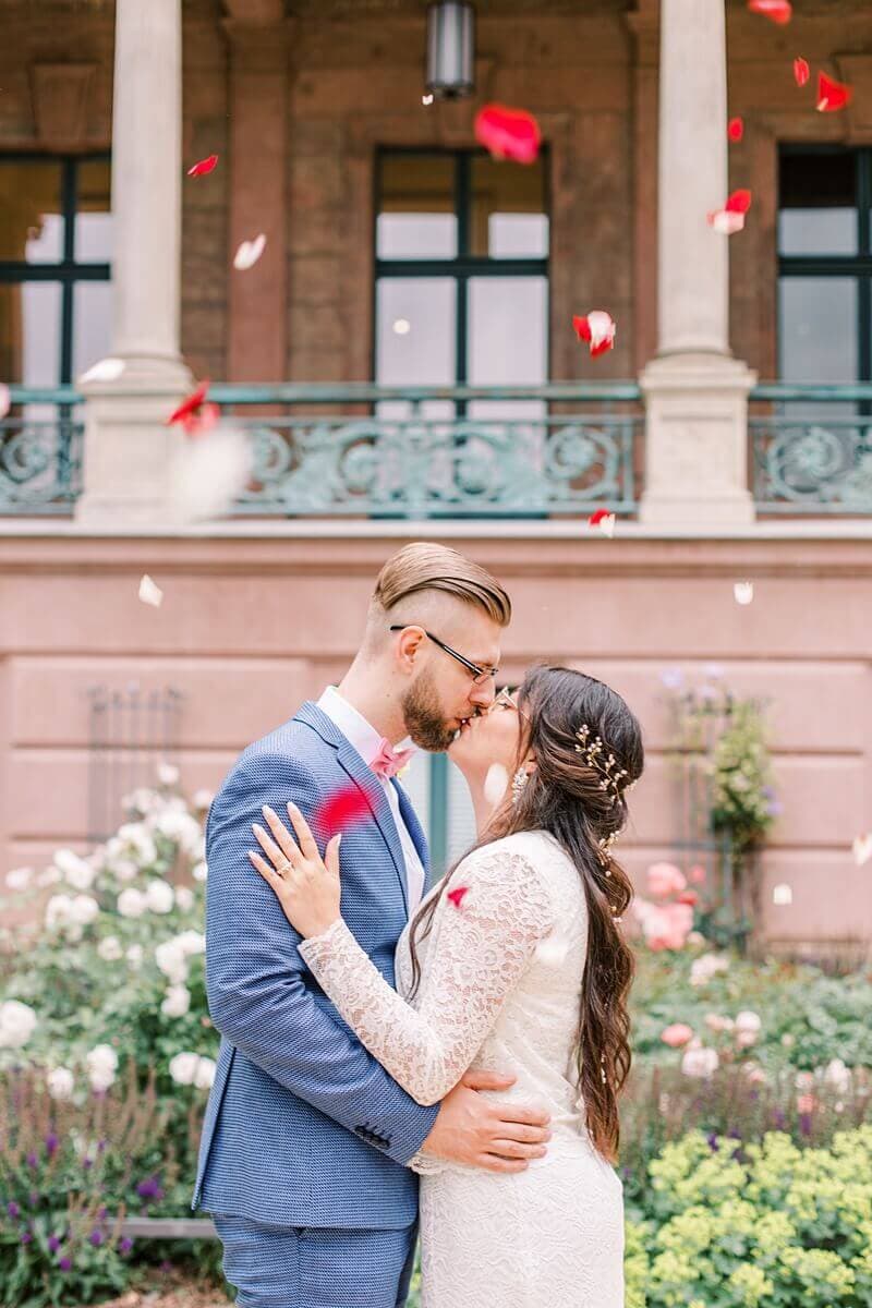 Hochzeitspaar küsst sich unter Blütenregen