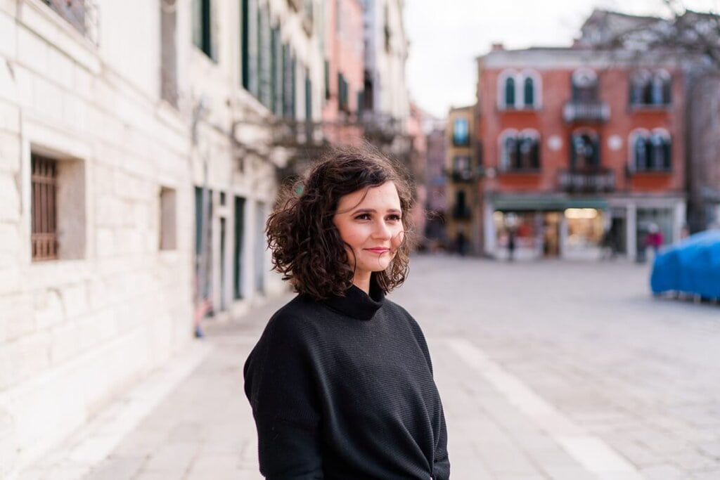 Frau mit Locken in Venedig auf einem Platz. Die Haare wehen im Wind.