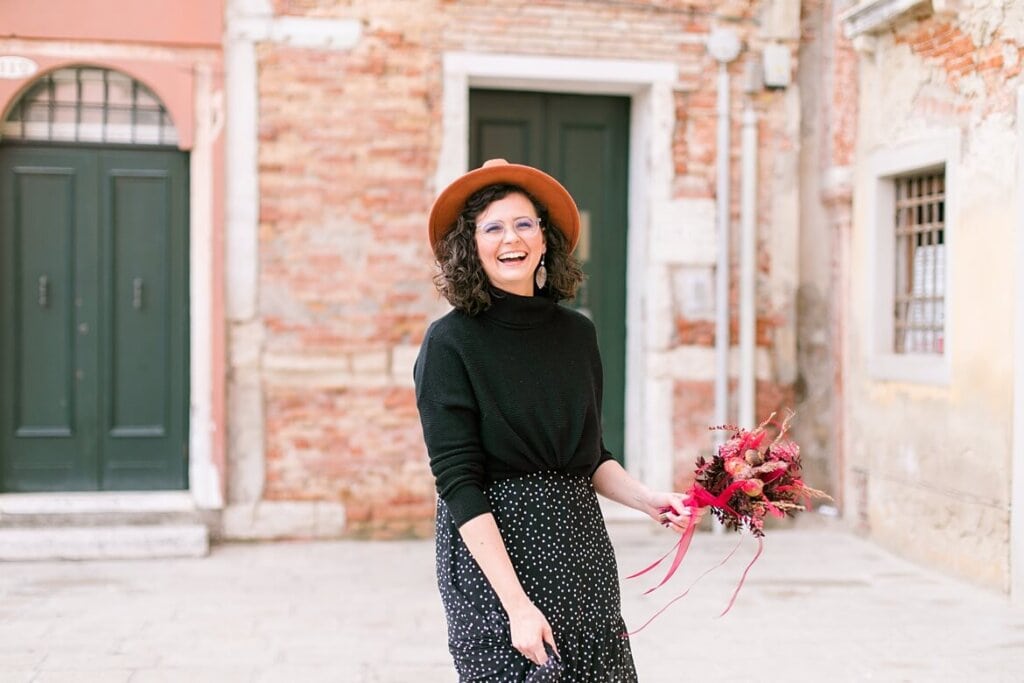 Frau in Venedig, lacht und hält einen Blumenstrauß in der Hand