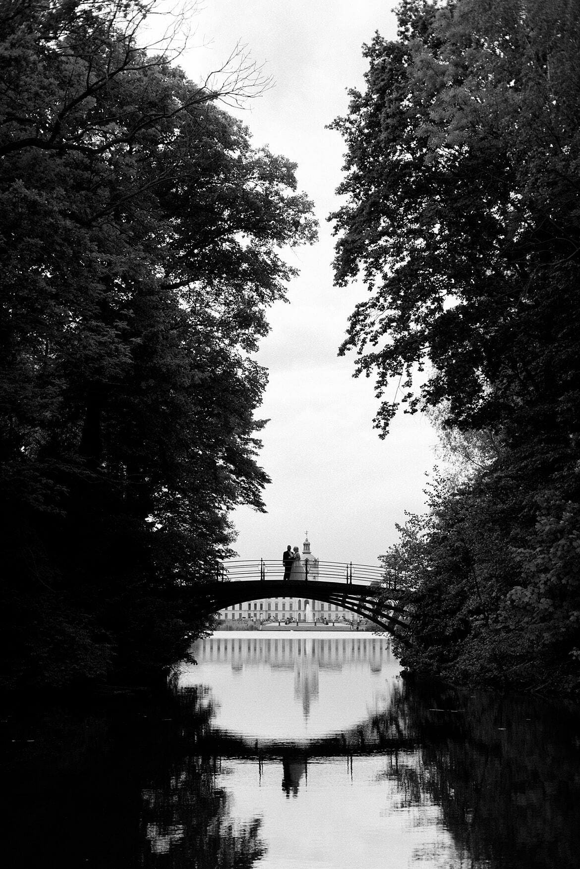 Schwarz Weiß Foto eines Brautpaares auf einer Brücke, im Hintergrund das Schloss Charlottenburg Berlin