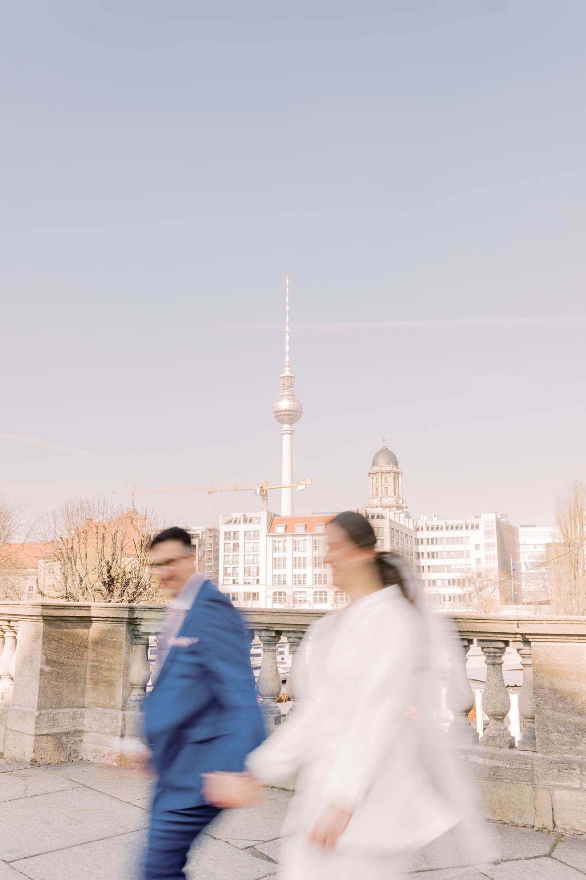 Brautpaar rennt und ist verschwommen, im Hintergrund sieht man den Fernsehturm in Berlin Mitte