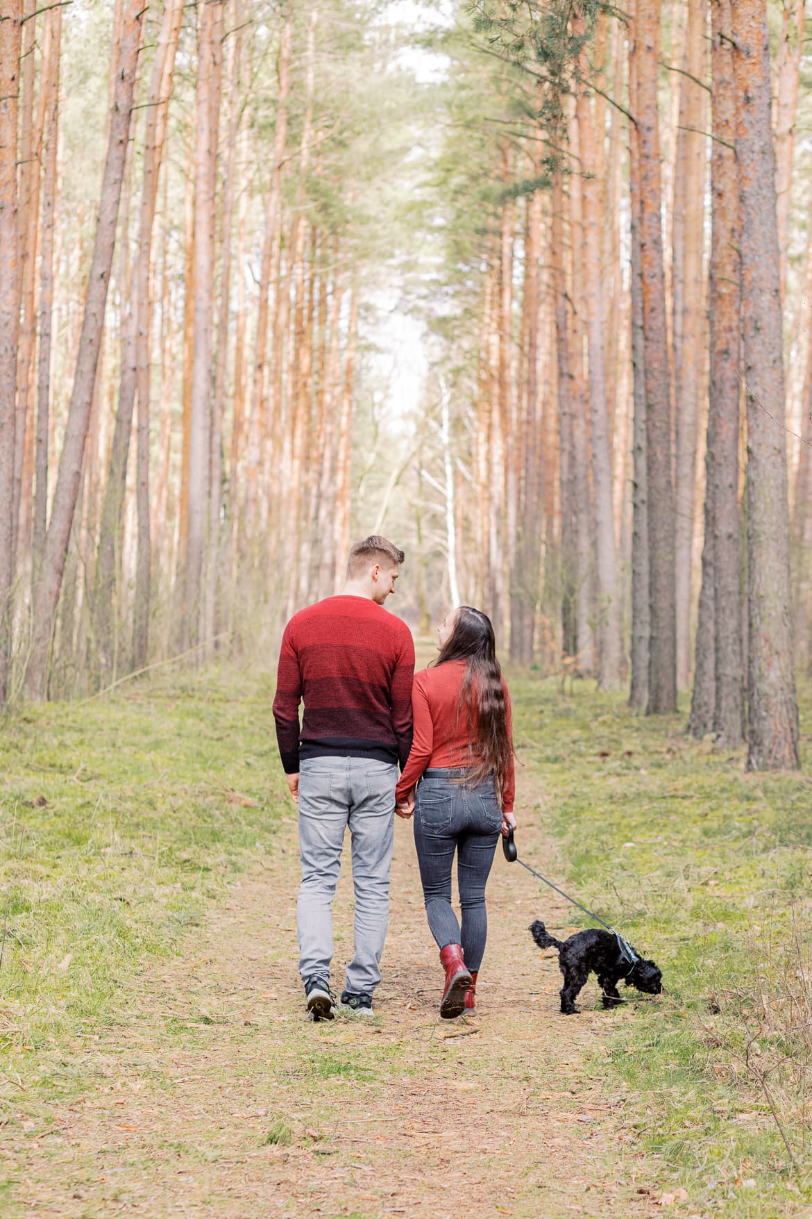 Ein Paar spaziert mit ihrem Hund durch den Wald