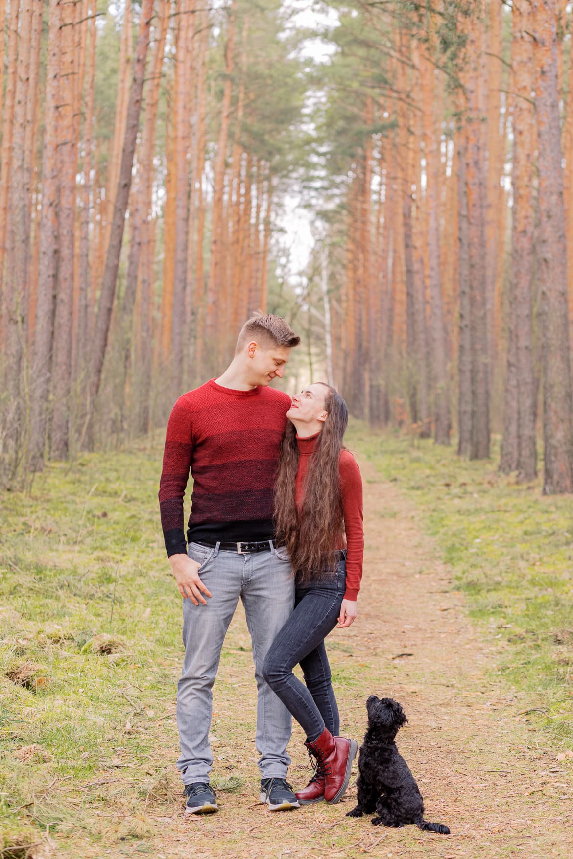 Pärchen mit Hund im Wald, sie schauen sich an