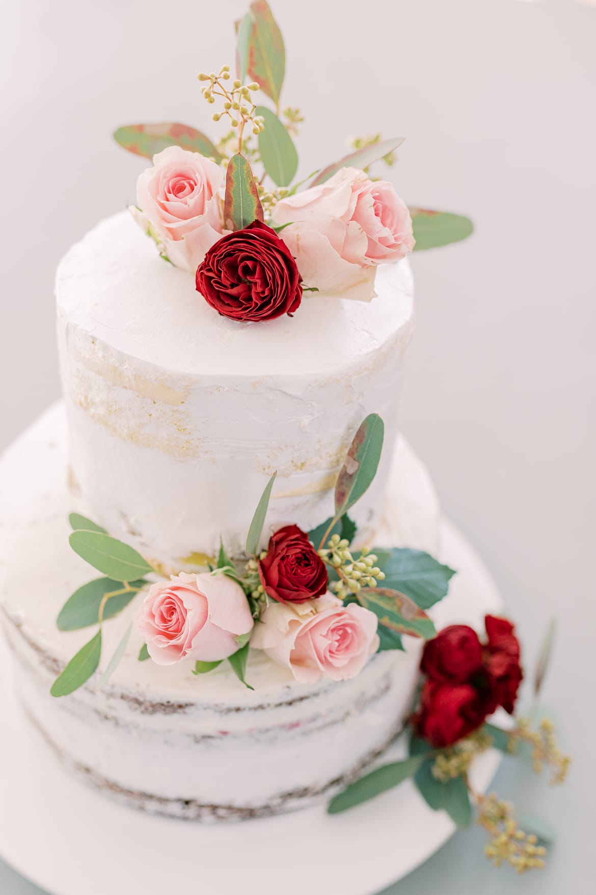 Hochzeitstorte mit roten und rosanen Rosen und weißen Fondant