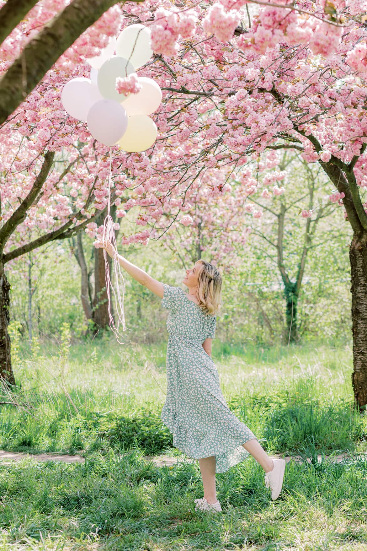 Eine Frau hat Luftballons in der Hand, es sieht so aus als würde sie mit ihnen wegfliegen