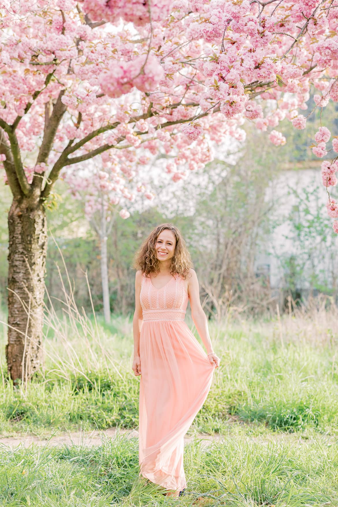 Eine Frau unter Kirschblüten im rosa Abendkleid