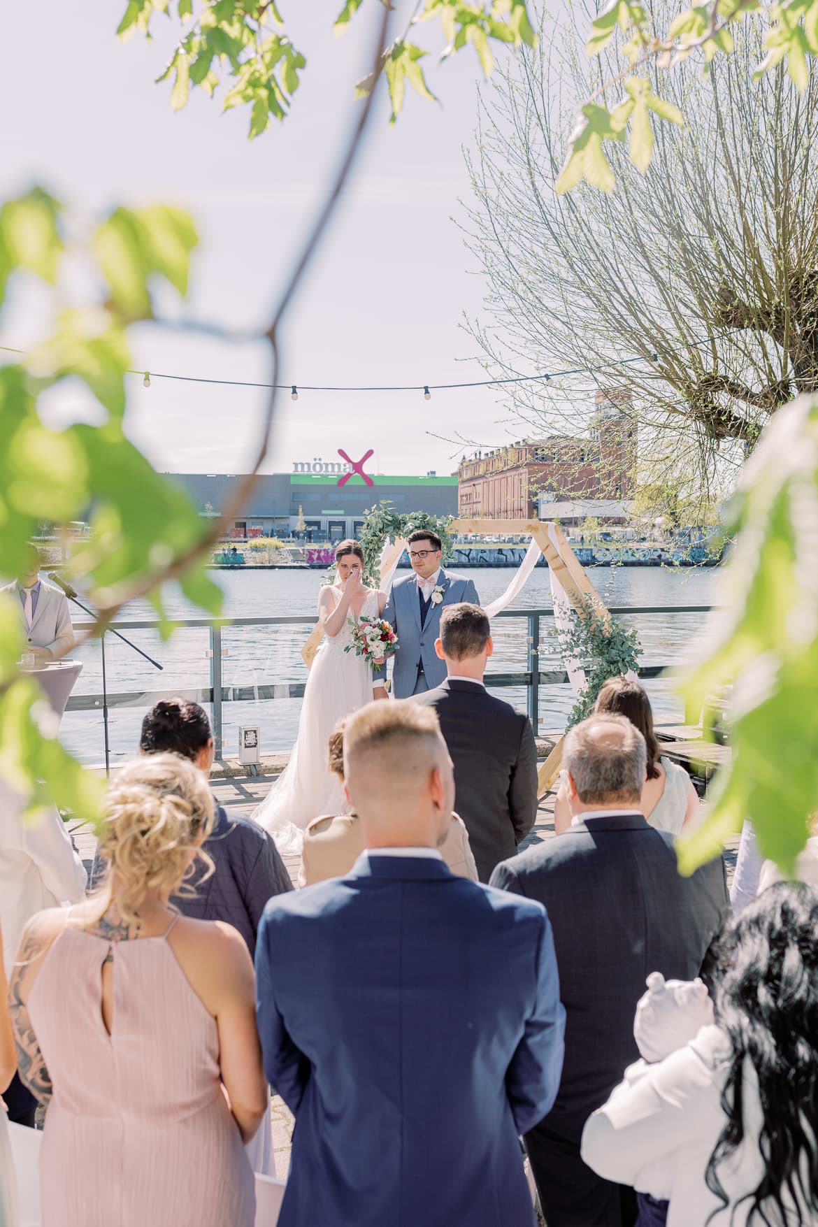 Gäste stehen bei einer Hochzeit während sich das Brautpaar das Ja Wort gibt