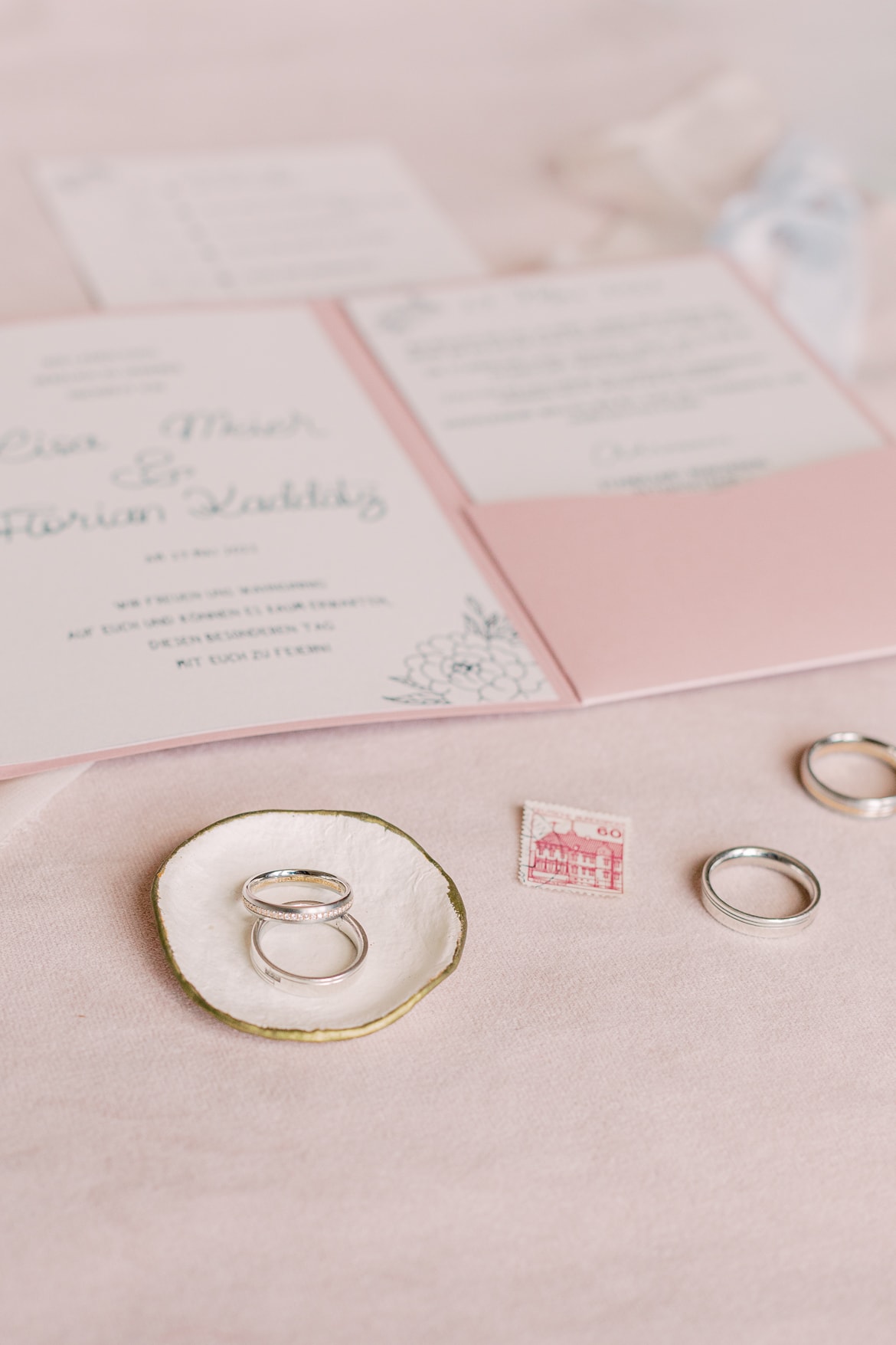 Einladungskarten und Ringe für eine Hochzeit auf rosa Hintergrund