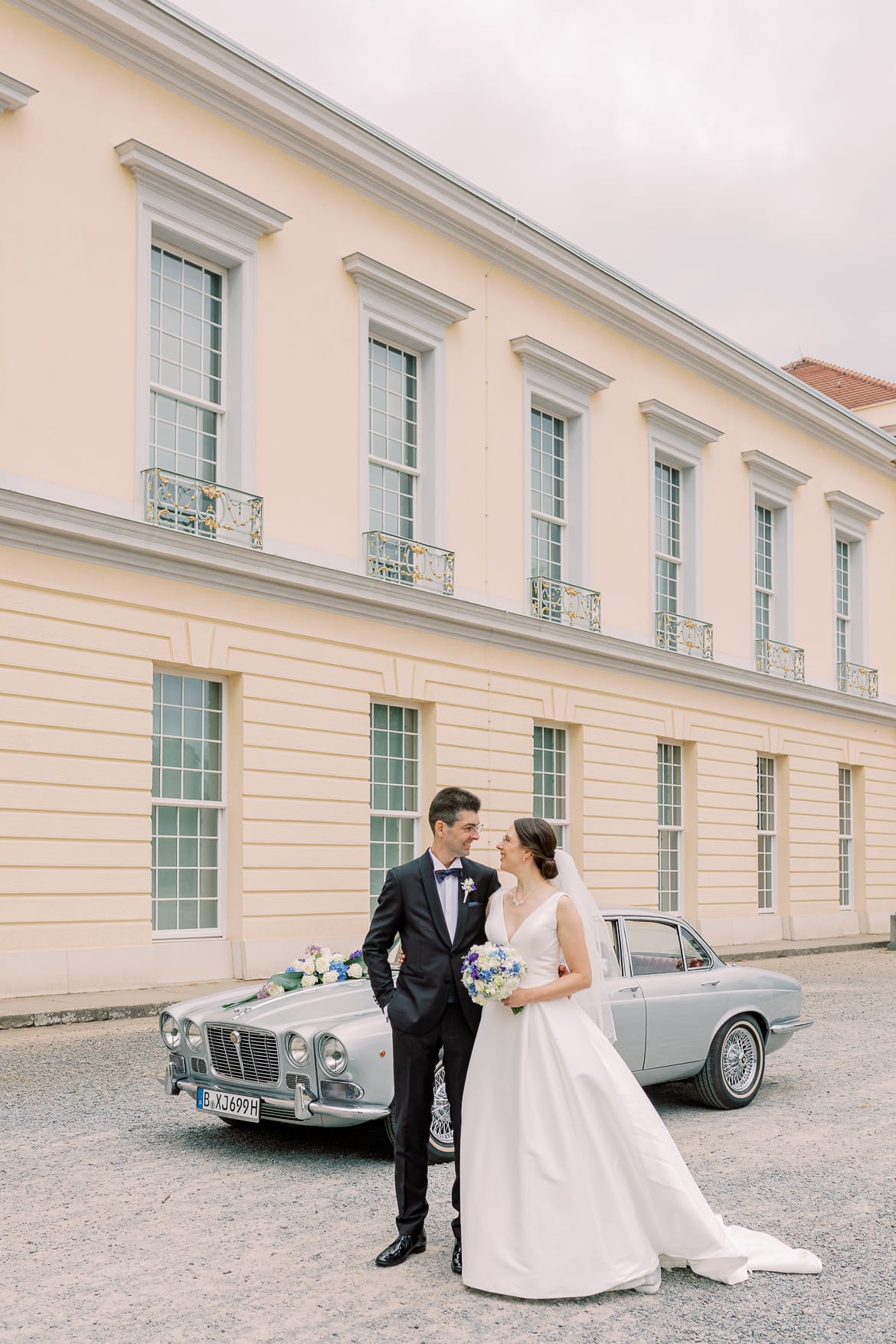 Brautpaar vor einem Oldtimer auf einem Schlossgelände