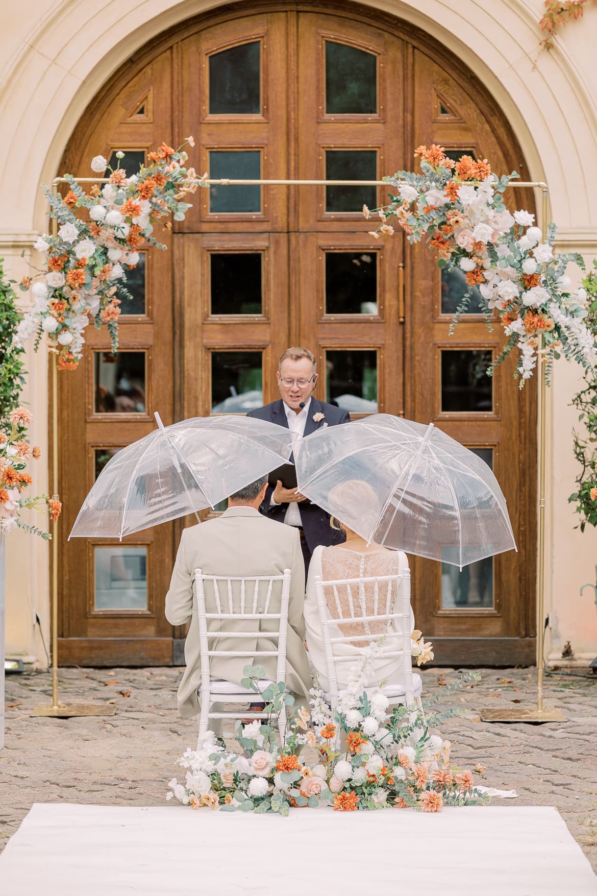 Braut und Bräutigam mit Regenschirmen zur freien Trauung im Schloss Glienicke