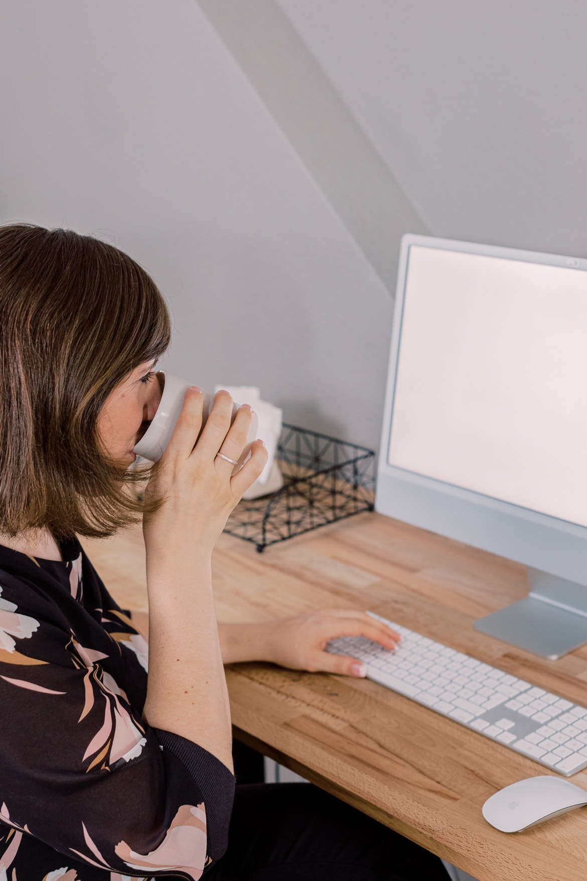 Eine Frau trinkt Kaffee an einem Computer