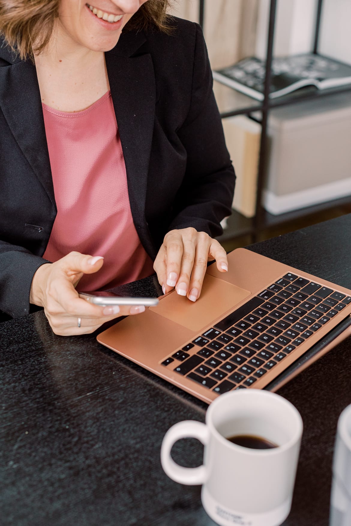 Man sieht eine Frau mit einem Handy and einem Laptop