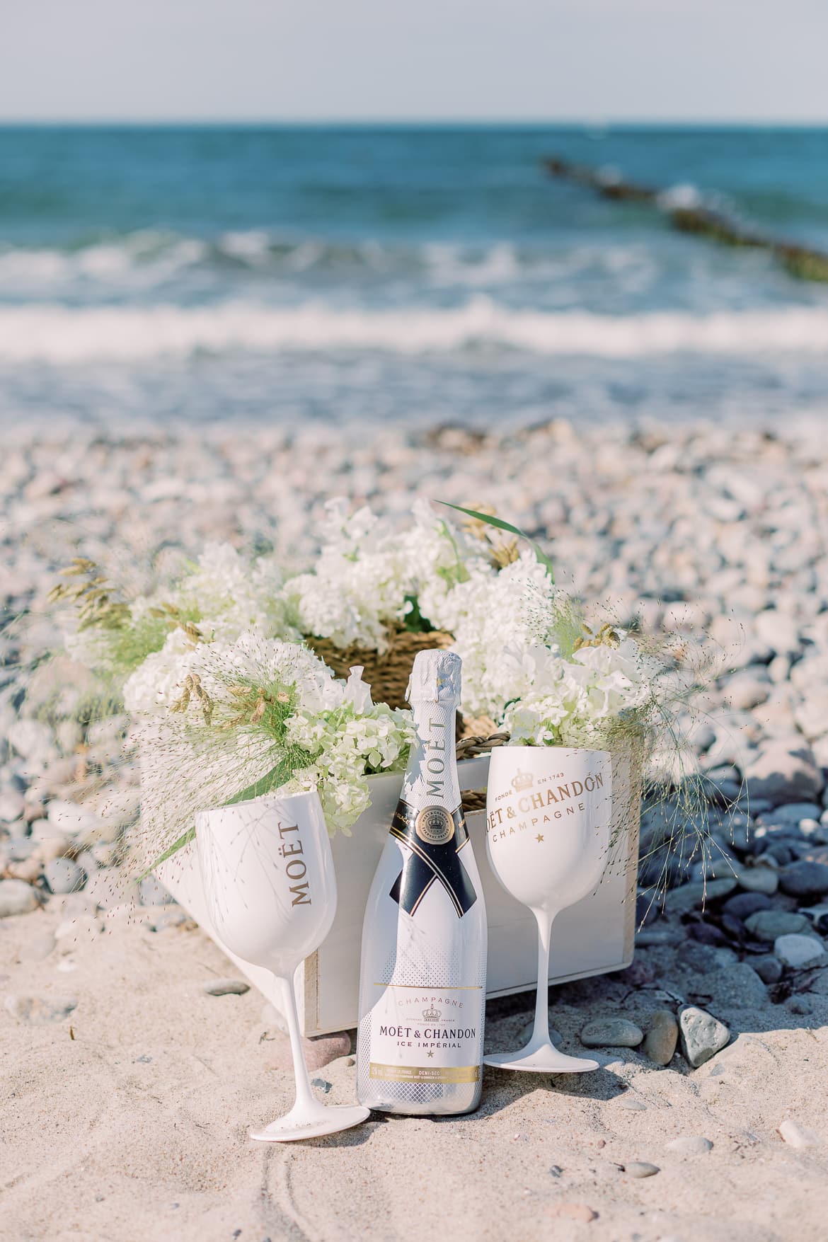 Champagner mit Blumen in einer Kiste am Strand