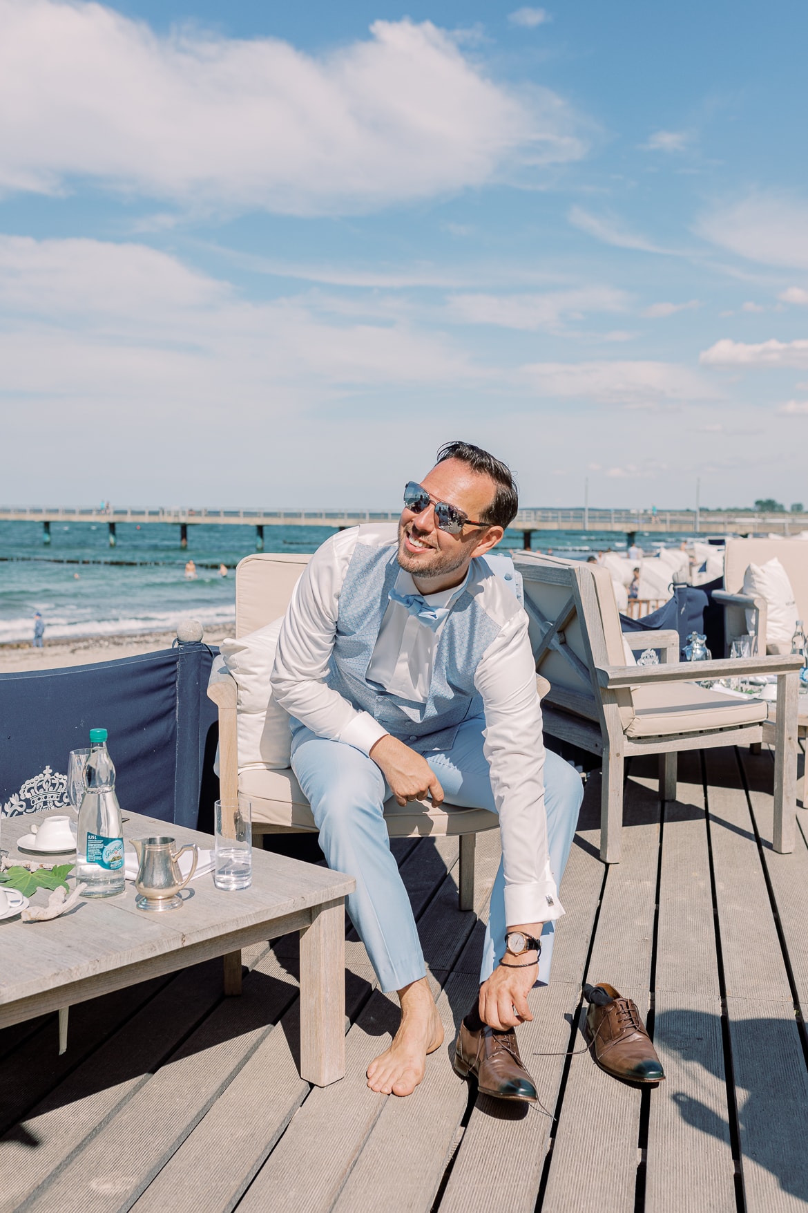 Der Bräutigam zieht sich für den Strand die Schuhe aus