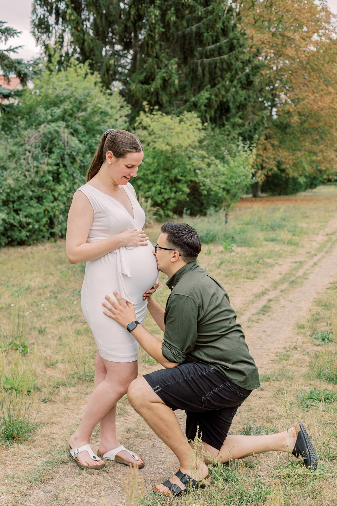 Ein Mann küsst den Babybauch seiner Frau