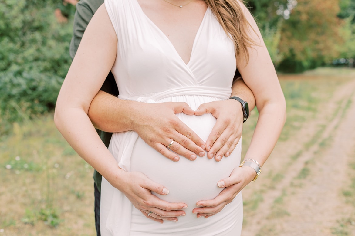 Werdende Eltern kuscheln und halten den Bauch fest