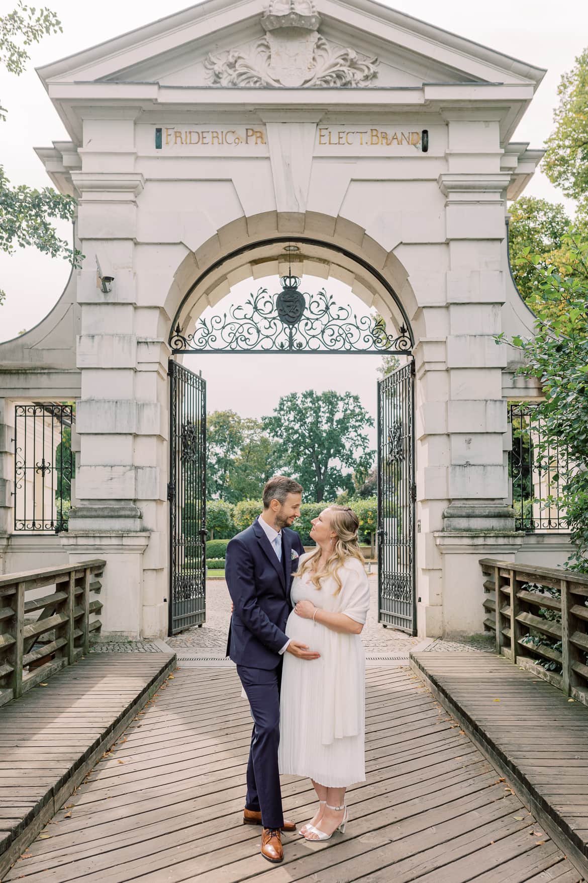 Hochzeitspaar umarmt sich vor dem Schlosstor zum Schloss Köpenick Berlin