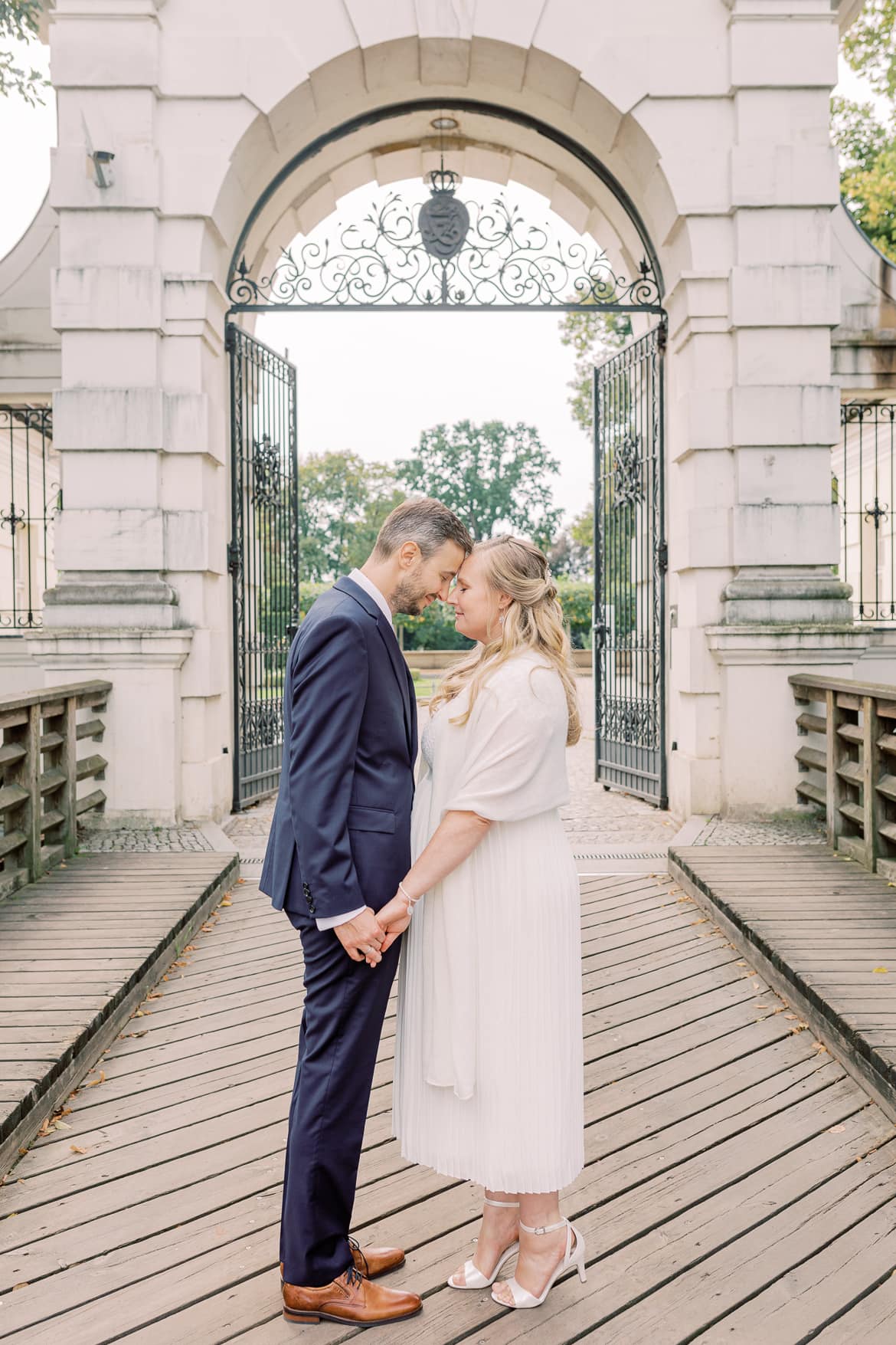 Hochzeitspaar umarmt sich innig vor dem Tor des Schloss Köpenick Berlin