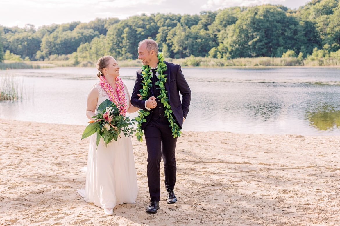 Hochzeitspaar spaziert am Ufer eines Sees