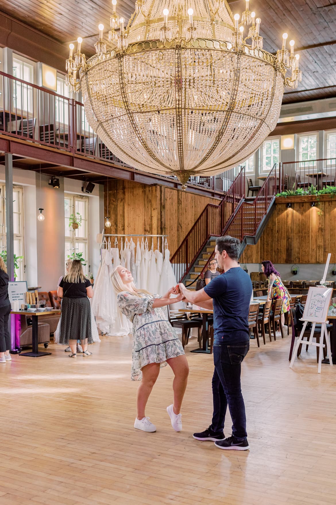 Ein Paar in Sommeroutfit tanzt eine Choreografie ihres Hochzeitstanzes in einer alten Turnhalle