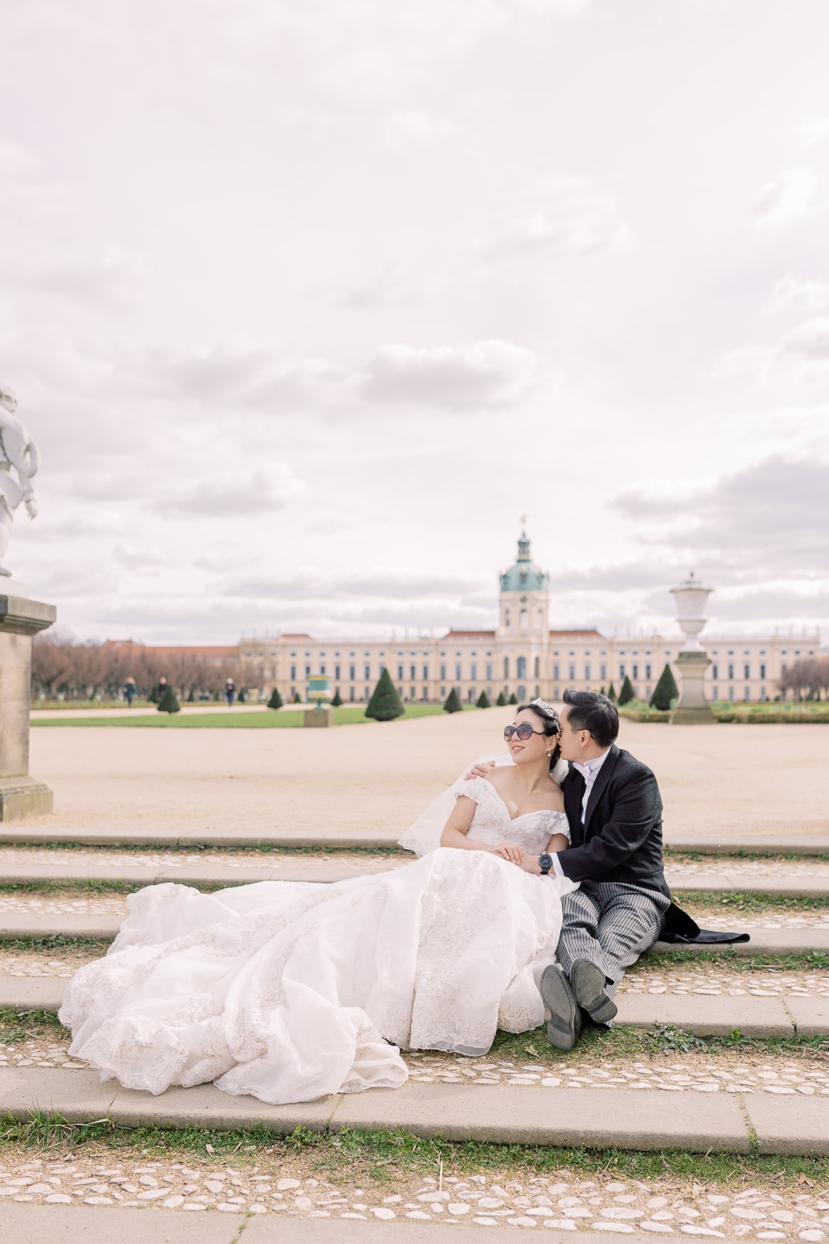 Hochzeitspaar sitzt auf einer Treppe im Park und hat Sonnenbrillen auf