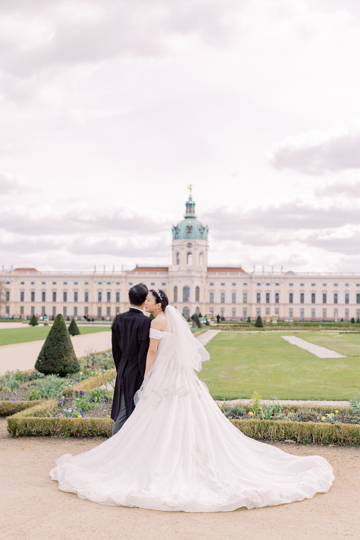 Hochzeitspaar schmust im Park und schaut auf ein Schloss