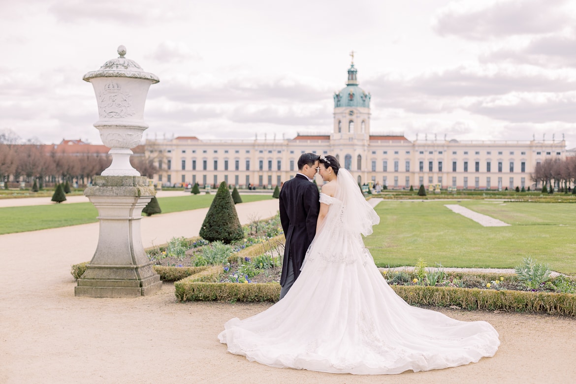 Hochzeitspaar kuschelt im Park vor einem Schloss