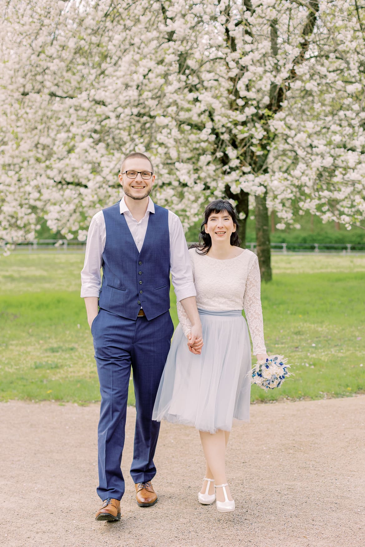 Hochzeitspaar vor einem blühenden Baum im Park