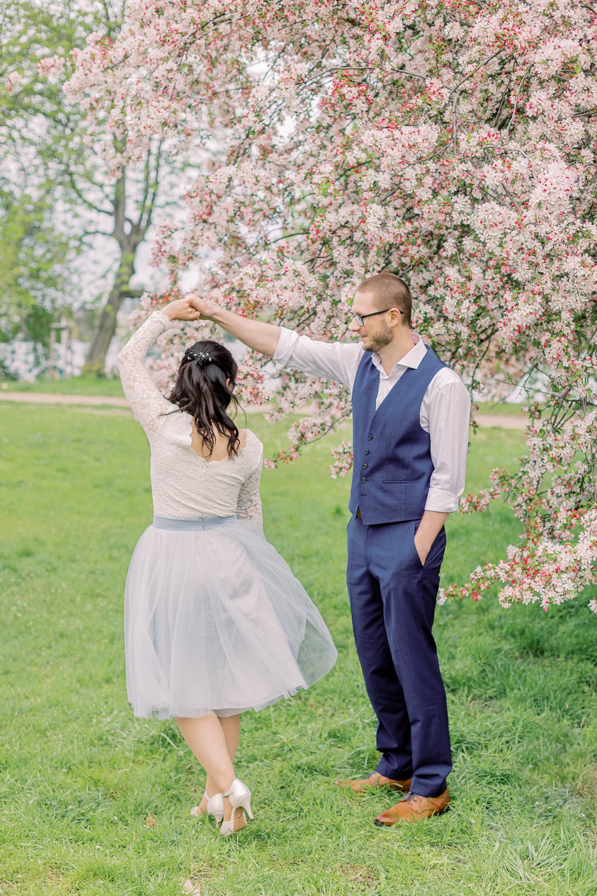 Hochzeitspaar tanzt vor einem blühenden Baum im Park