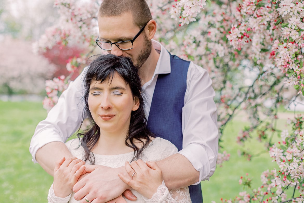 Hochzeitspaar vor einem blühenden Baum im Park