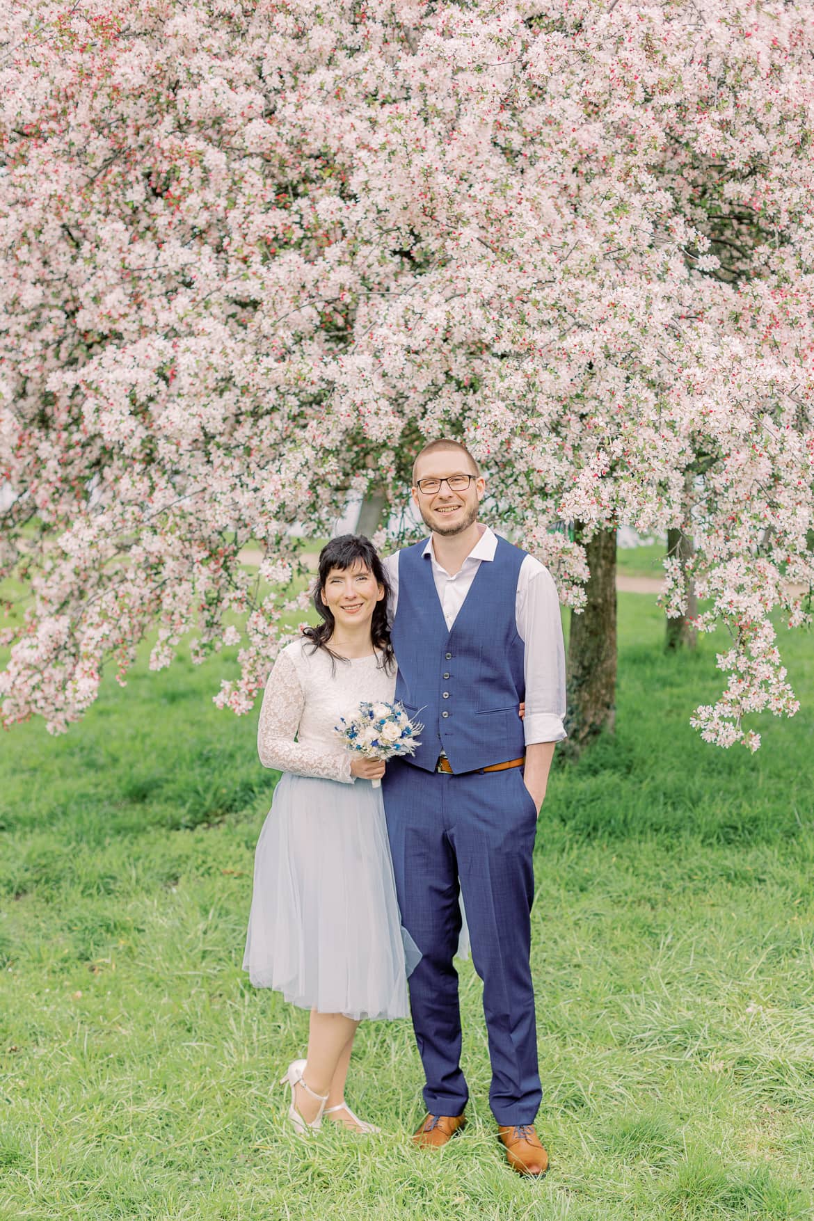 Hochzeitspaar vor einem blühenden Baum im Park