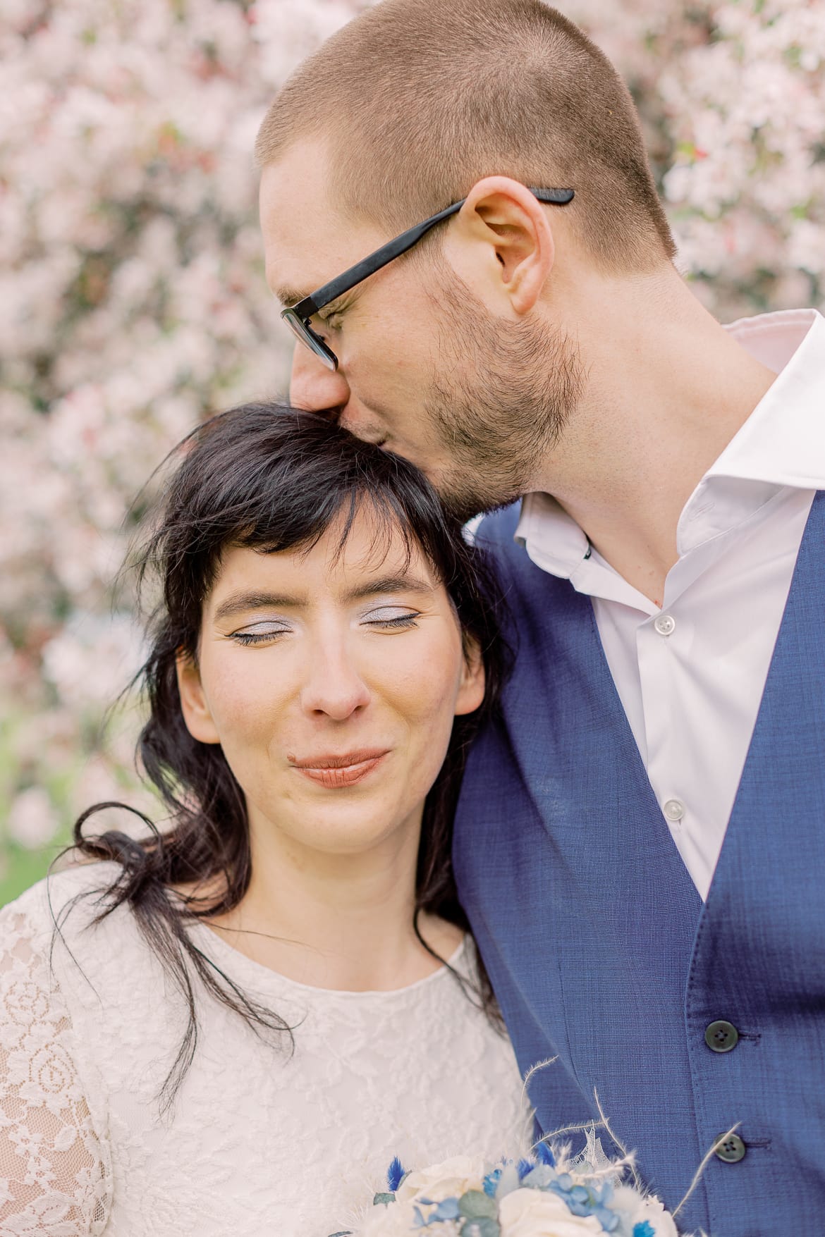 Hochzeitspaar vor einem blühenden Baum im Park