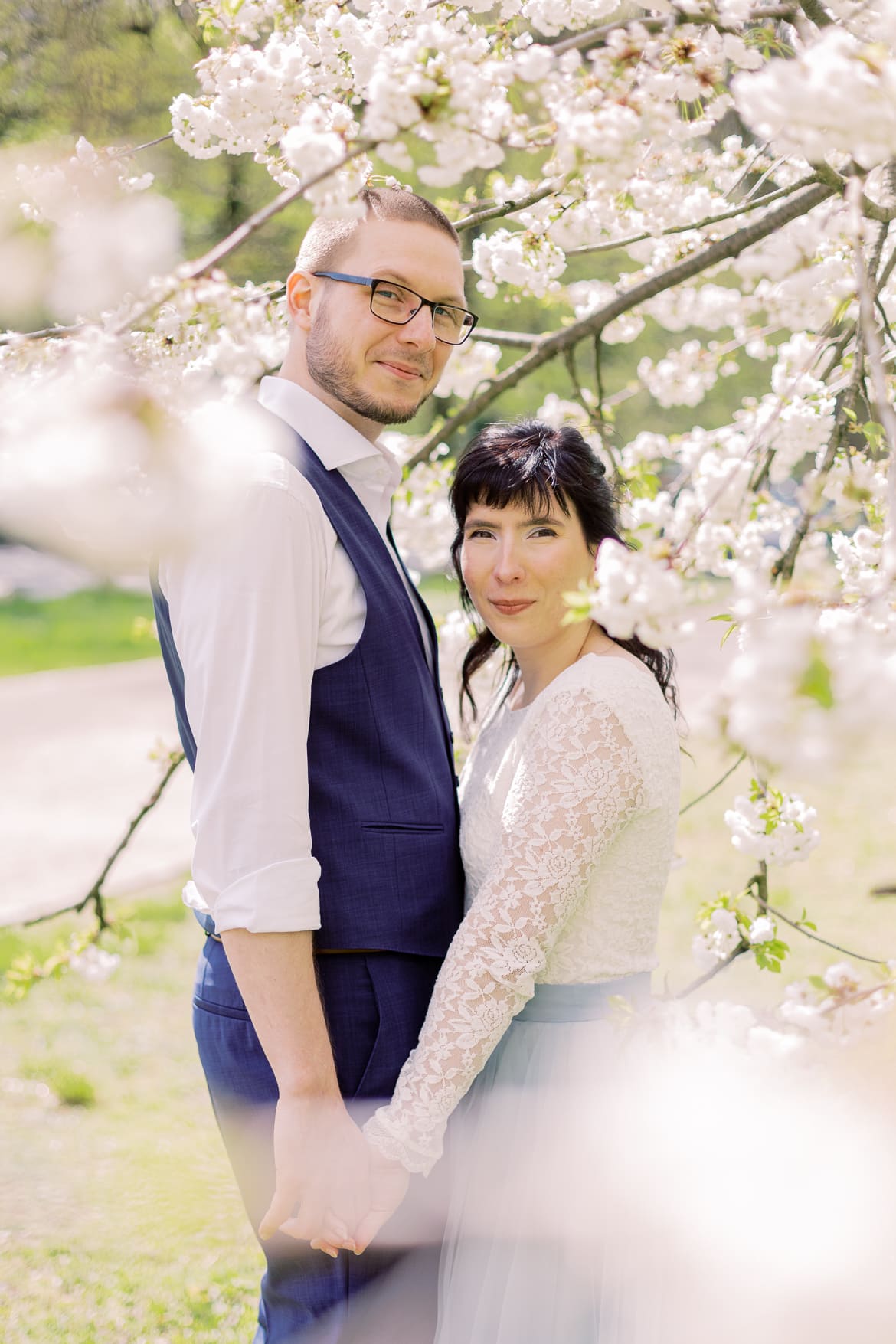 Hochzeitspaar vor einem blühenden Baum im Park