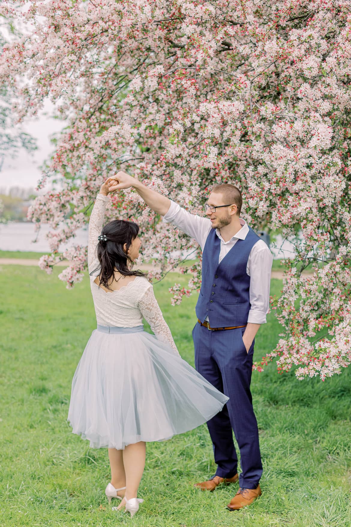 Hochzeitspaar tanzt vor einem blühenden Baum im Park