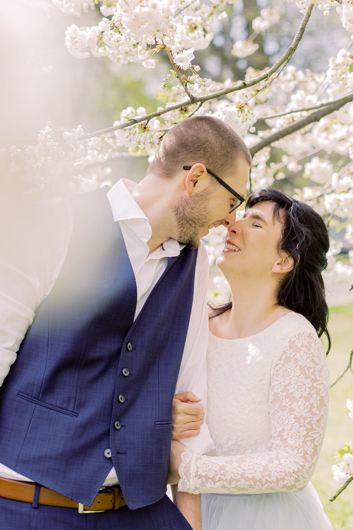 Hochzeitspaar vor einem blühenden Baum im Park