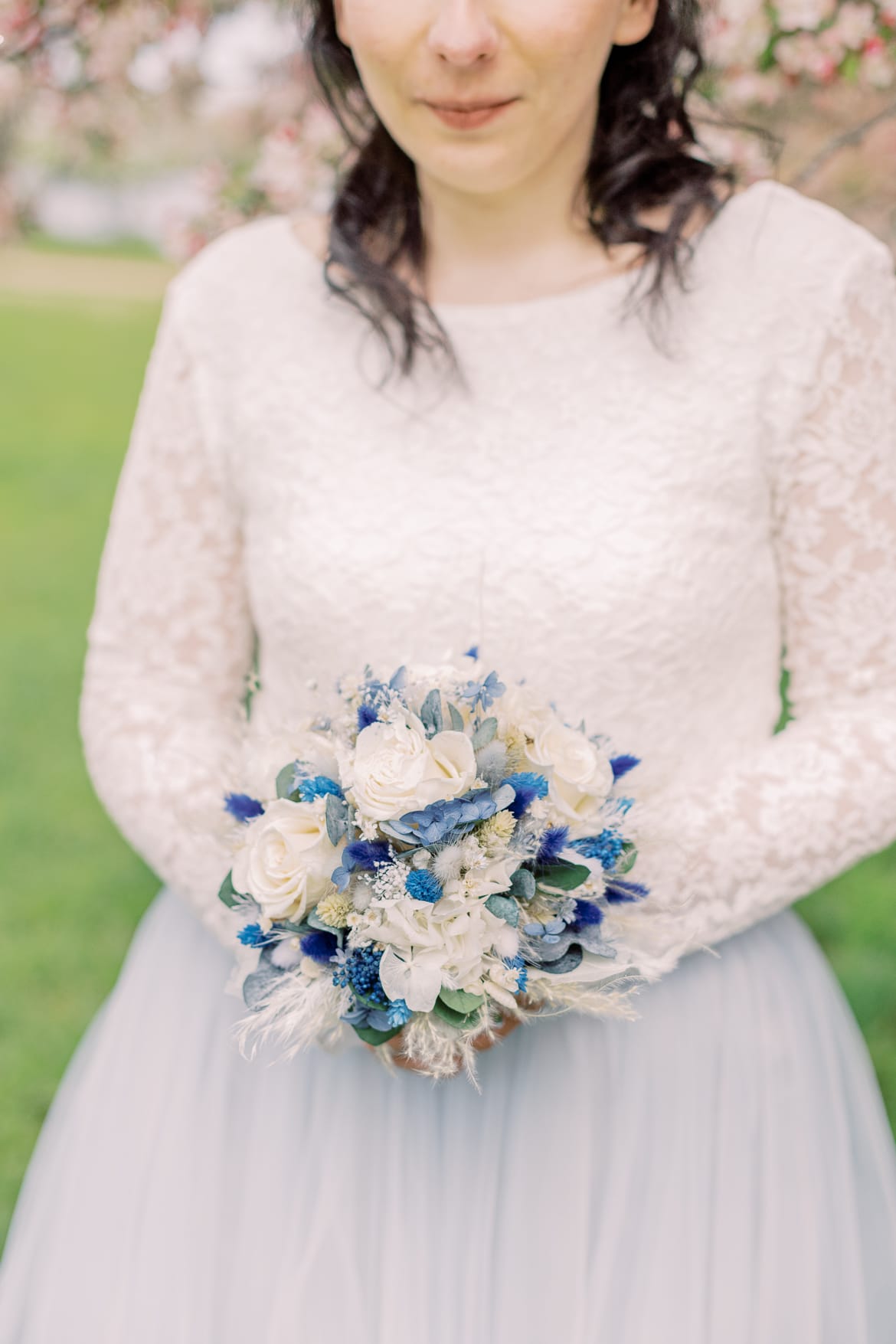 Braut hält einen Brautstrauß aus blauen Trockenblumen in der Hand