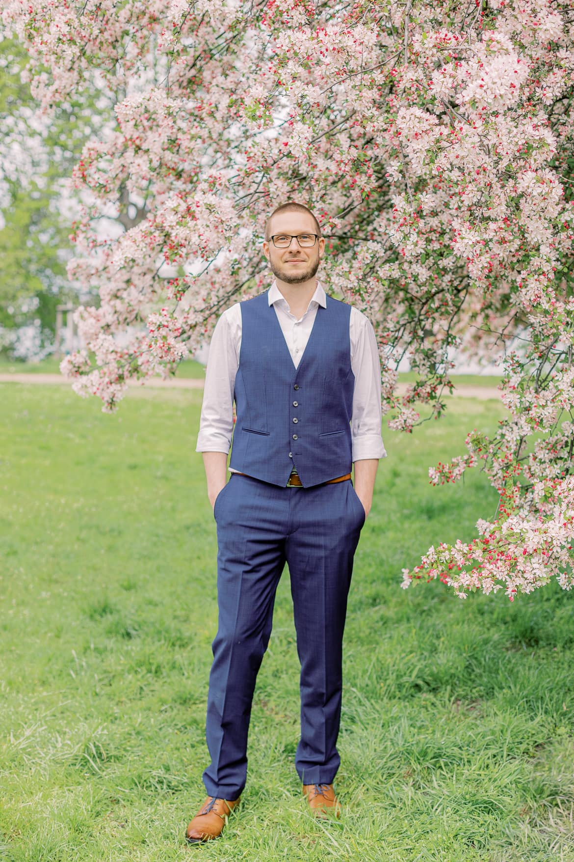 Bräutigam vor einem blühenden Baum im Park