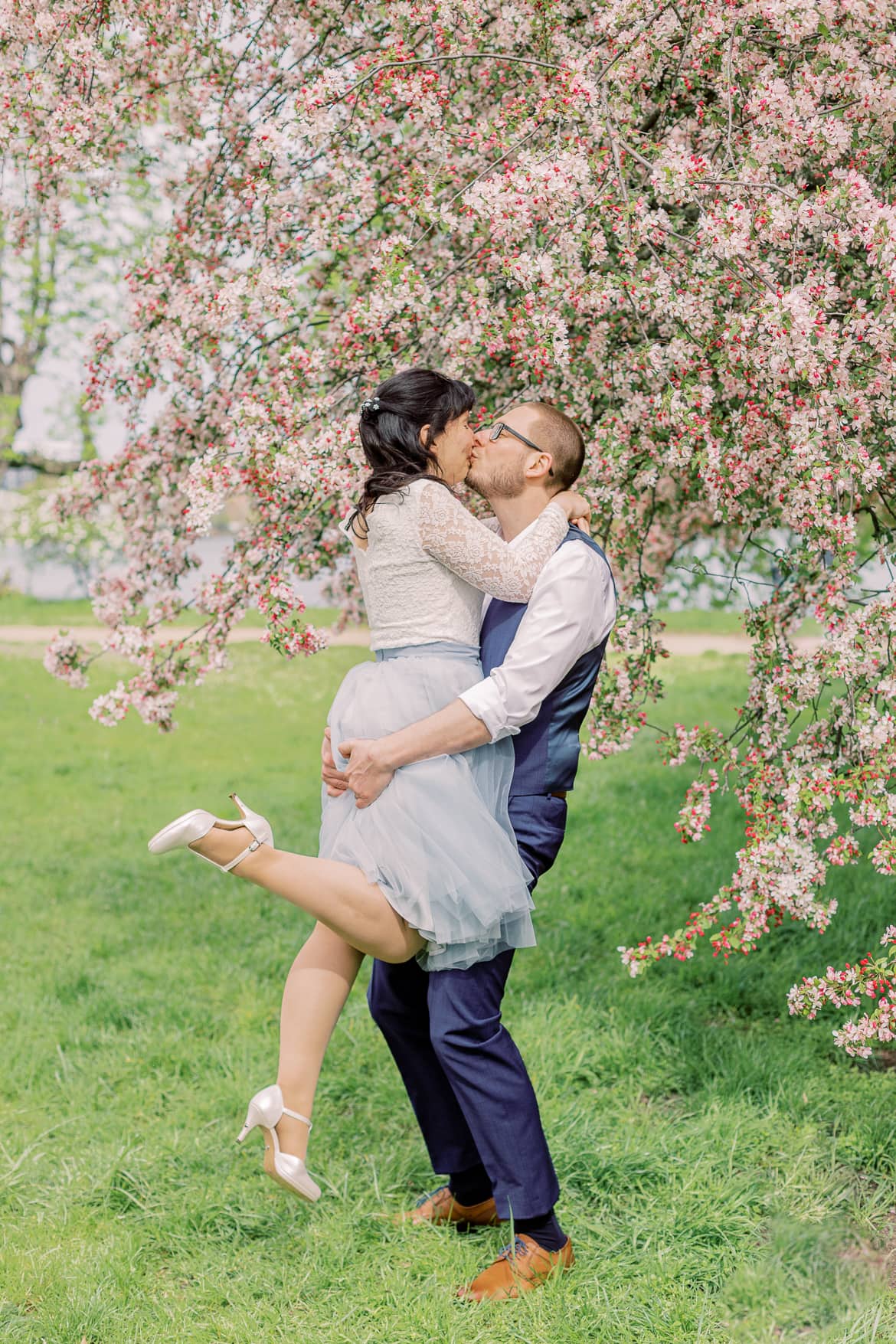 Hochzeitspaar vor einem blühenden Baum im Park