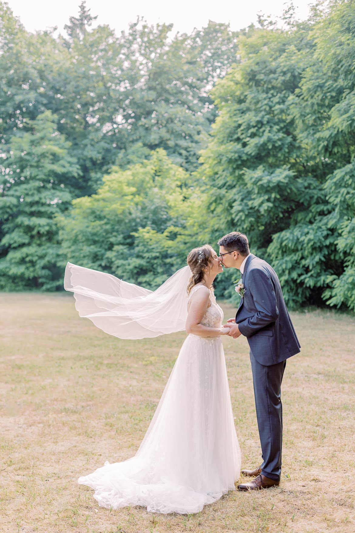 Hochzeitspaar küsst sich und der Schleier weht im Wind