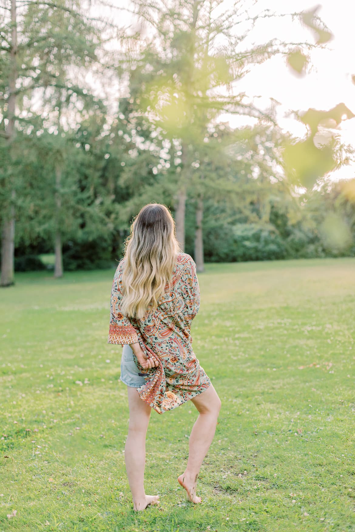 Frau mit blonden Haaren und Kimono in der Abendsonne im Park