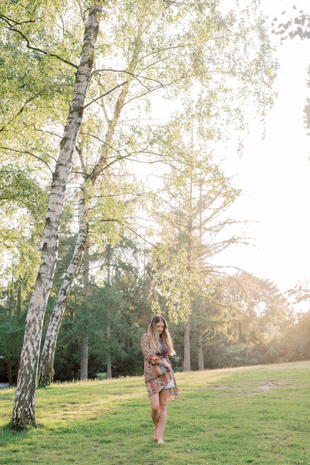 Frau mit blonden Haaren und Kimono in der Abendsonne im Park