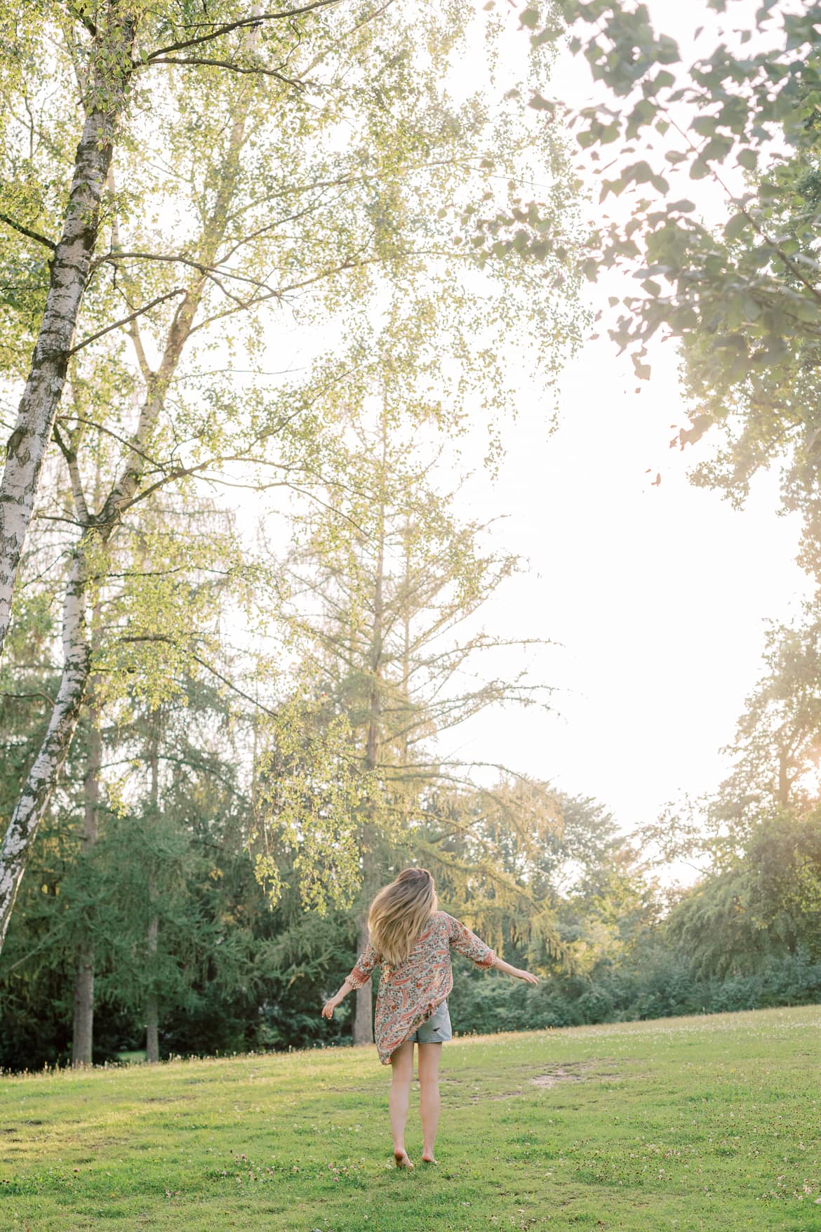 Frau mit blonden Haaren und Kimono in der Abendsonne im Park