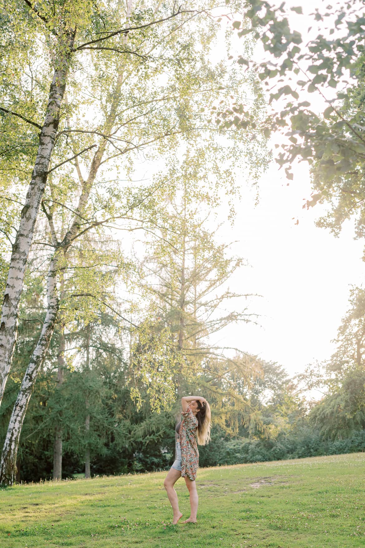 Frau mit blonden Haaren und Kimono in der Abendsonne im Park