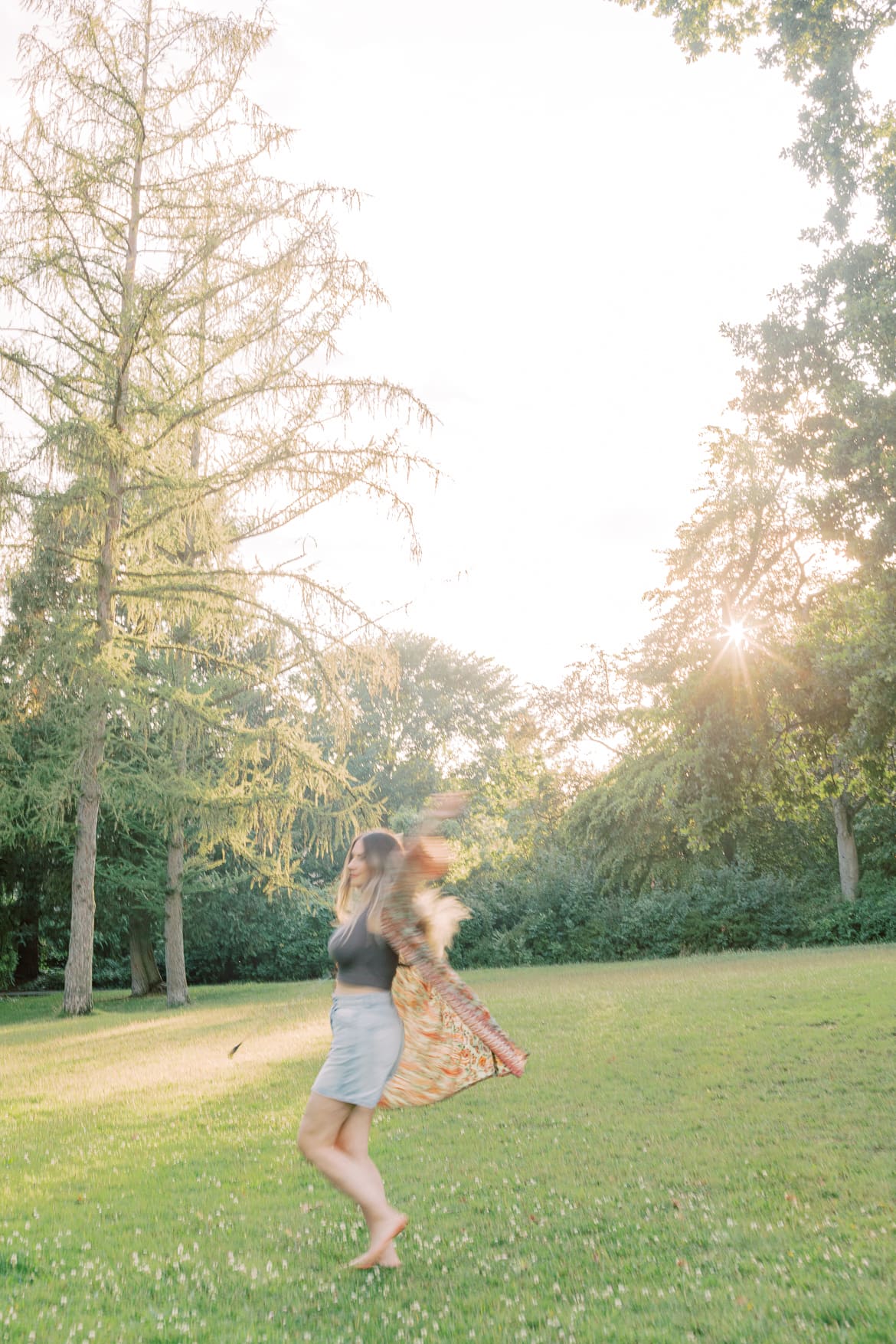 Frau tanzt mit blonden Haaren und Kimono in der Abendsonne im Park